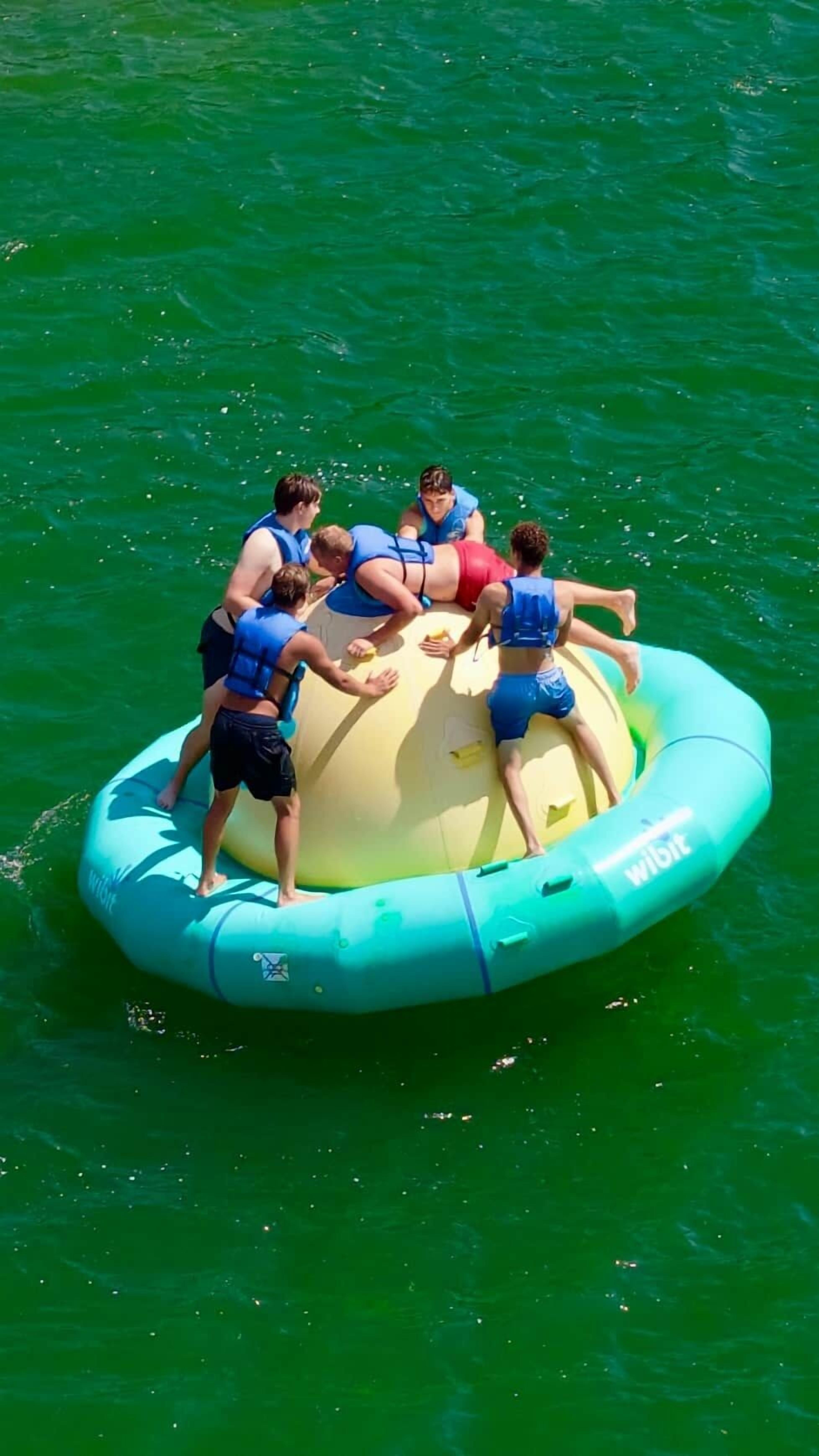 Un groupe de personnes se trouve sur un grand radeau gonflable, sur une étendue d’eau.