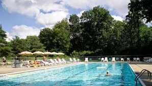 A rectangular swimming pool with clear blue water, surrounded by lounge chairs and umbrellas.