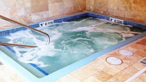 A hot tub with a tiled interior and a wooden ladder.