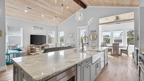 A spacious kitchen with a large island, wooden flooring, and a high ceiling with exposed beams. - Coastal Sunsets - Vacation Rental in 30A with Private Pool (Santa Rosa Beach)