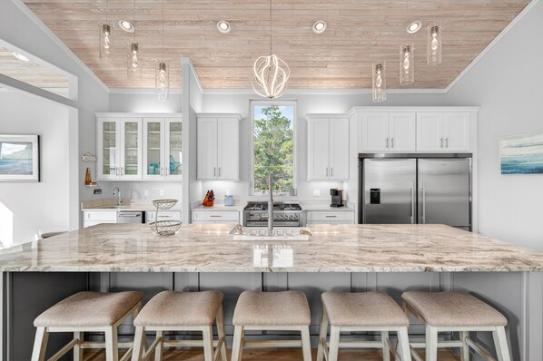 A modern kitchen with a large island, stainless steel appliances, and pendant lighting. - Coastal Sunsets - Vacation Rental in 30A with Private Pool (Santa Rosa Beach)
