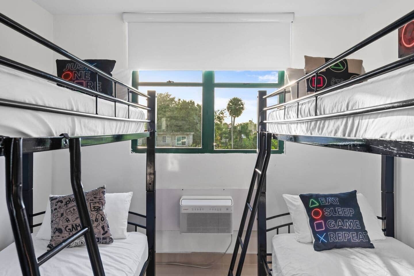 A bunk room with two beds, a window with a view, and a wall-mounted air conditioner.