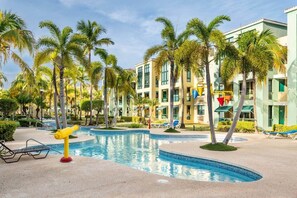 A resort pool area with palm trees, lounge chairs, and a swimming pool. - The Best Apartment in Aquatika (Vieques)