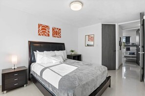 A modern bedroom with a large bed, bedside tables, and artwork on the walls. - The Best Apartment in Aquatika (Vieques)