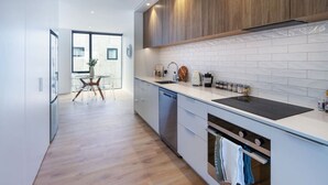 A modern kitchen with white cabinetry, a black stovetop, and a wooden floor. - 2-Bedroom w/ Carpark. Overlooks Central East Frame (Christchurch)