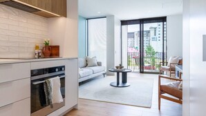 A modern kitchen with white cabinets, a built-in oven, and a small dining area with a round table and chairs. - 2-Bedroom w/ Carpark. Overlooks Central East Frame (Christchurch)