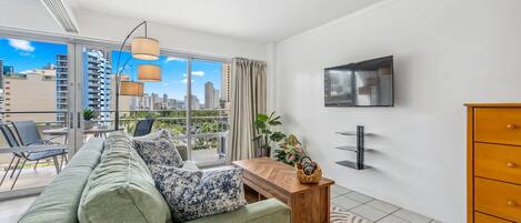 Ein modernes Wohnzimmer mit einem grünen Sofa, einem Holztisch und einem an der Wand montierten Fernseher.