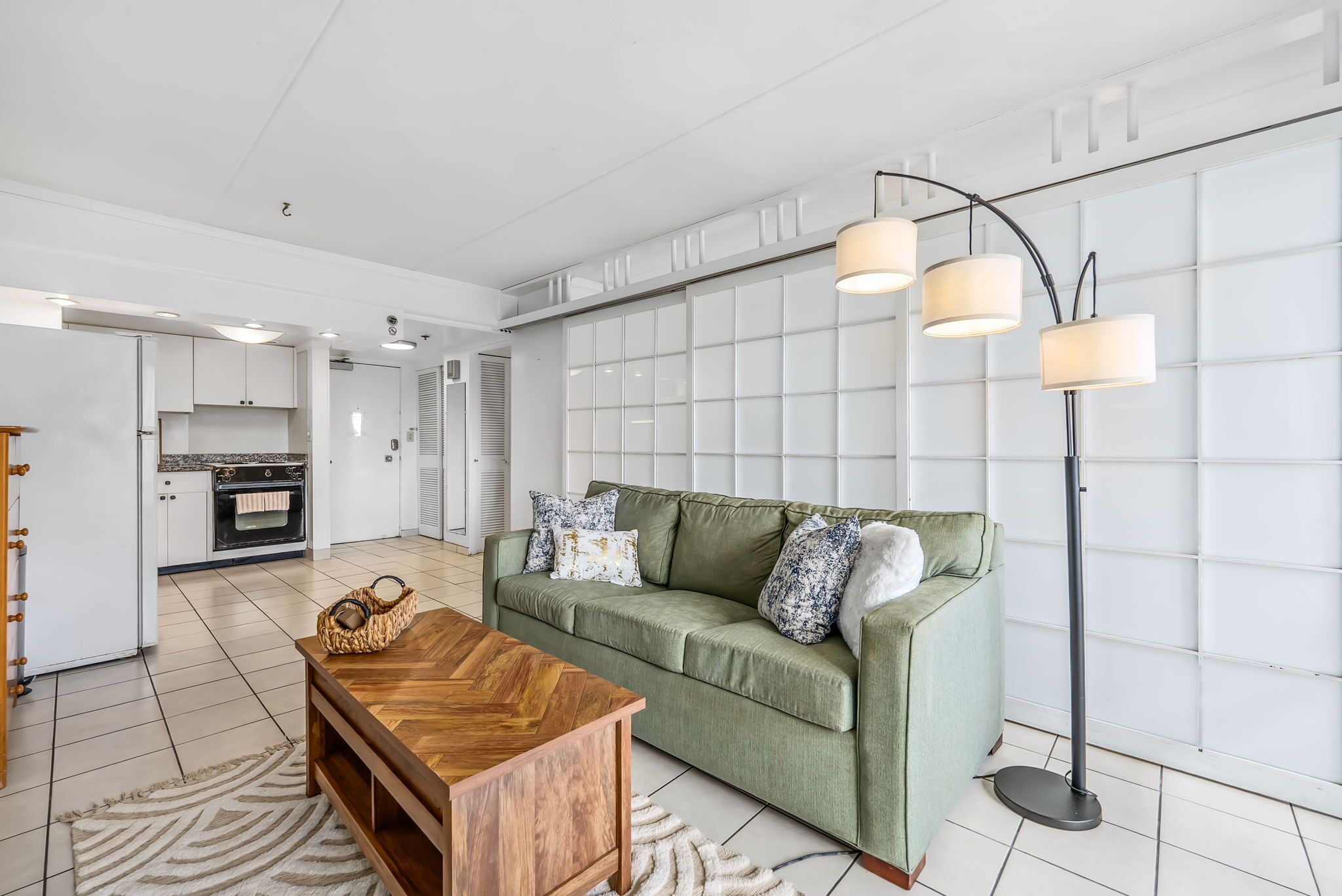 A modern living room with a green sofa, wooden coffee table, and a floor lamp.