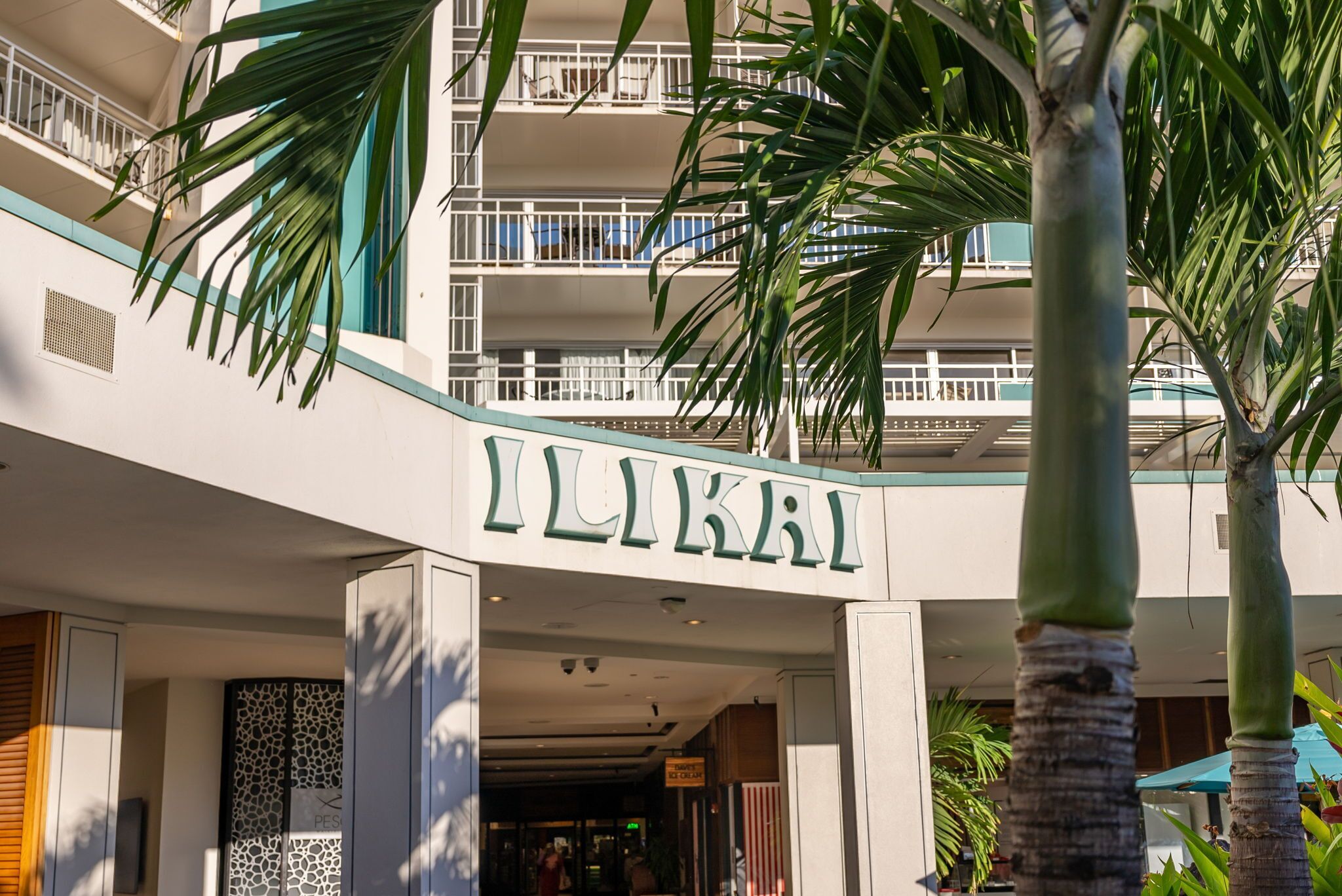A building entrance with the sign 'ILIKAI' and a modern architectural design with balconies and palm trees.