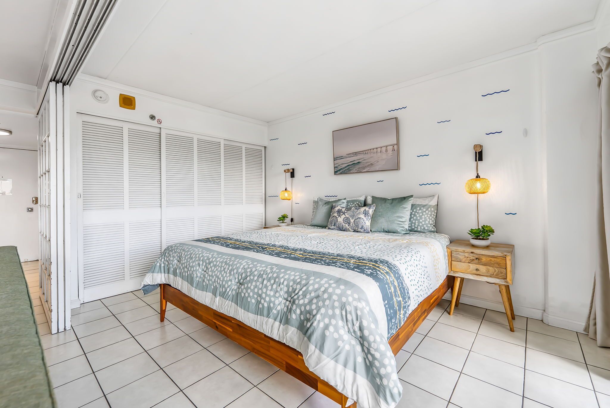 Een slaapkamer met een bed, nachtkastjes, een raam en een wandlamp.