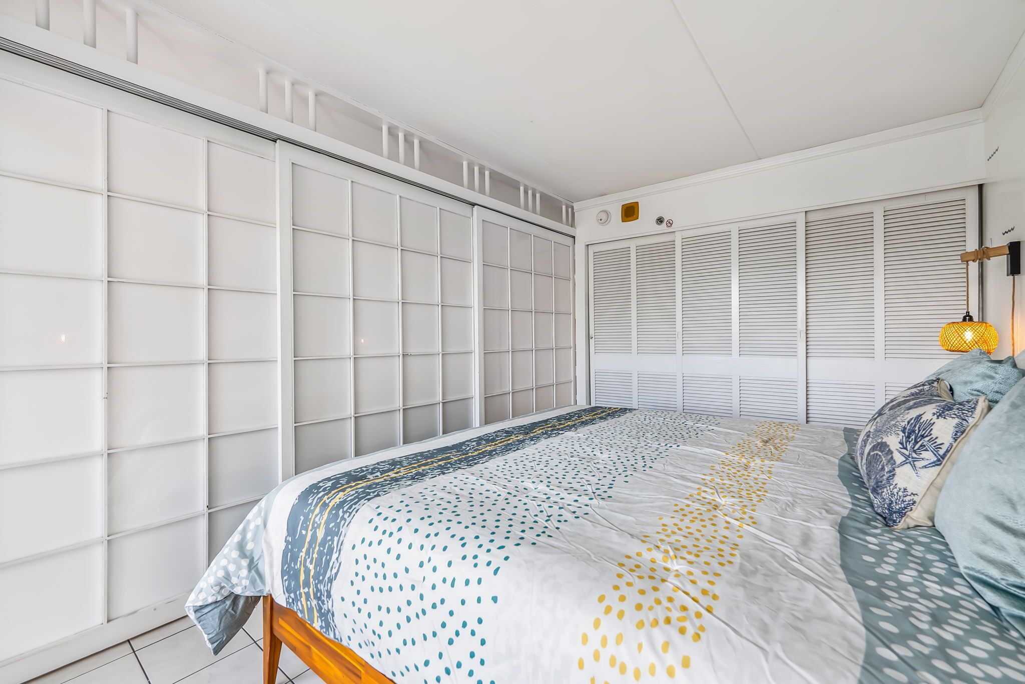 A bedroom with a bed, a wardrobe, and a window with blinds.