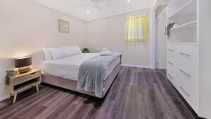 A bedroom with a bed, bedside table, lamp, and a wardrobe.
