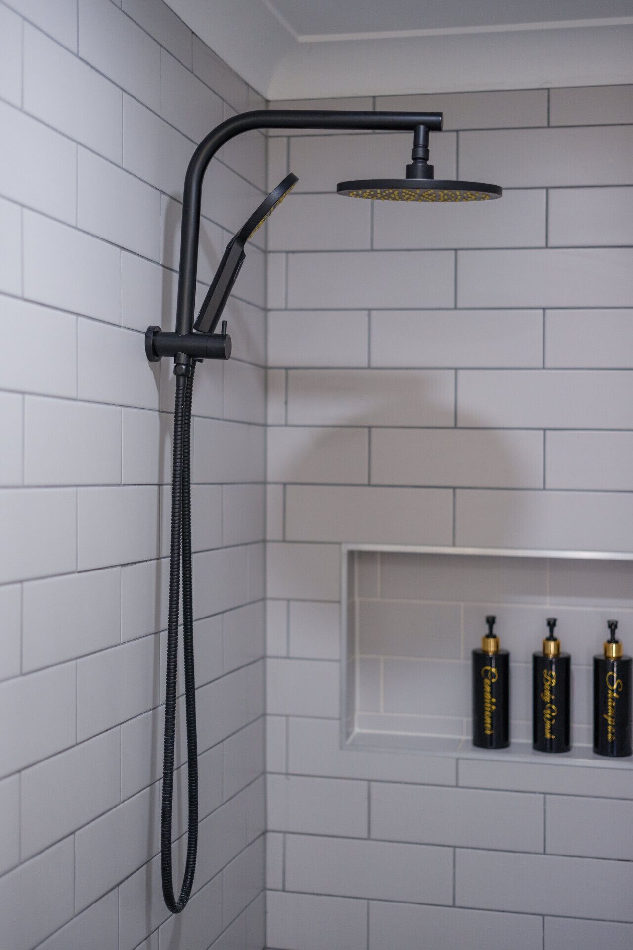 Eine Duschkabine mit Eckdusche, einem gebogenen schwarzen Brauseschlauch und einer Handbrause.