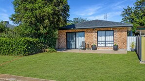 A two-story brick house with a flat roof, large windows, and a well-maintained lawn.