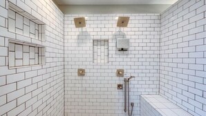 A bathroom with white subway tiles, a shower with a handheld showerhead, and a bench. - Welcome World Cup fans to this Spacious 5-bedroom house with Modern updates (Overland Park)