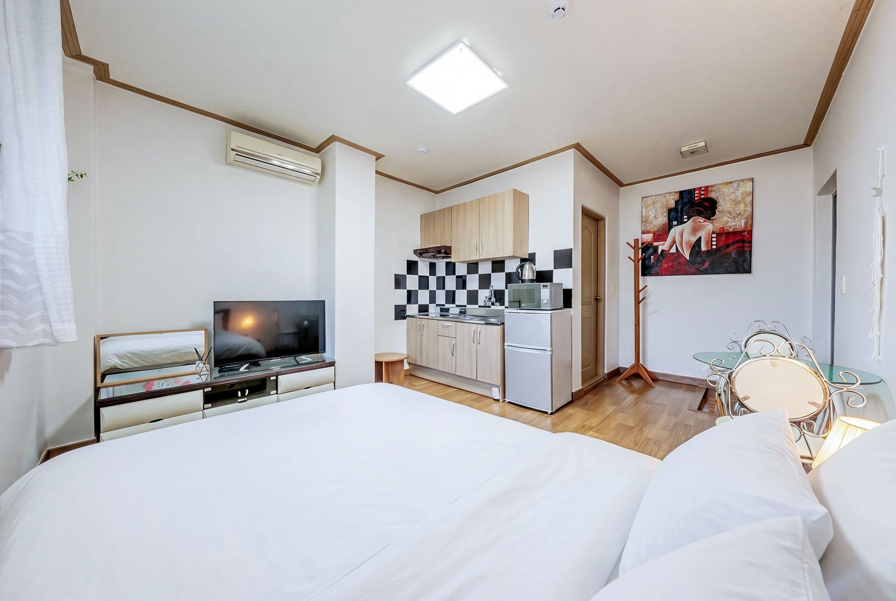 A hotel room with a bed, a TV, a kitchenette, and a dining area.