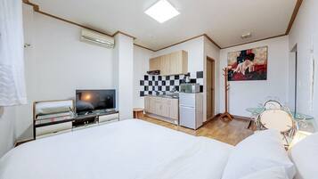 A hotel room with a bed, a TV, a kitchenette, and a dining area.