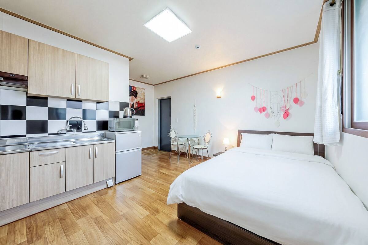 Une chambre d’hôtel moderne avec un plancher en bois, un lit, une kitchenette et un coin repas.