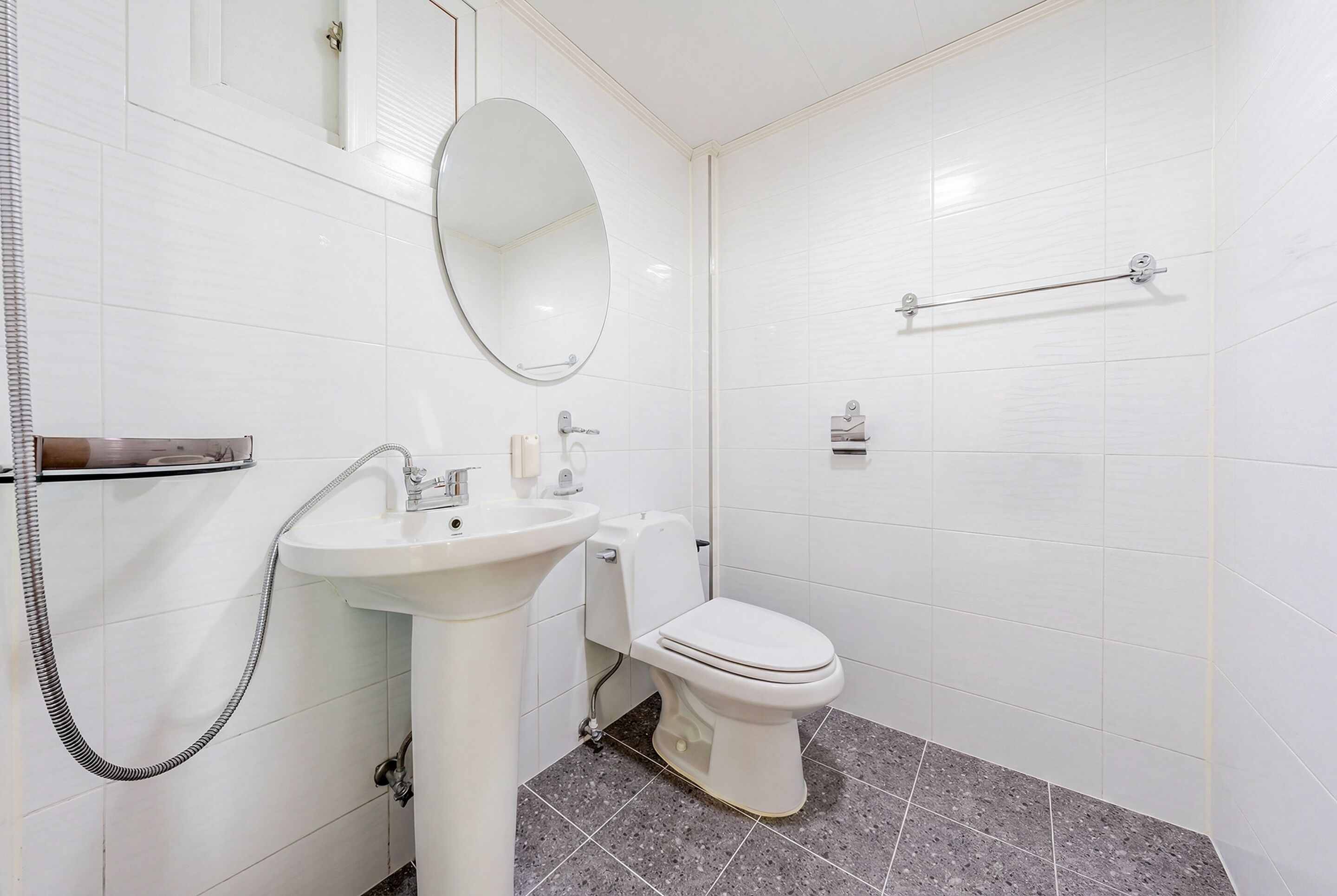A bathroom with a white sink, mirror, toilet, and towel rack.