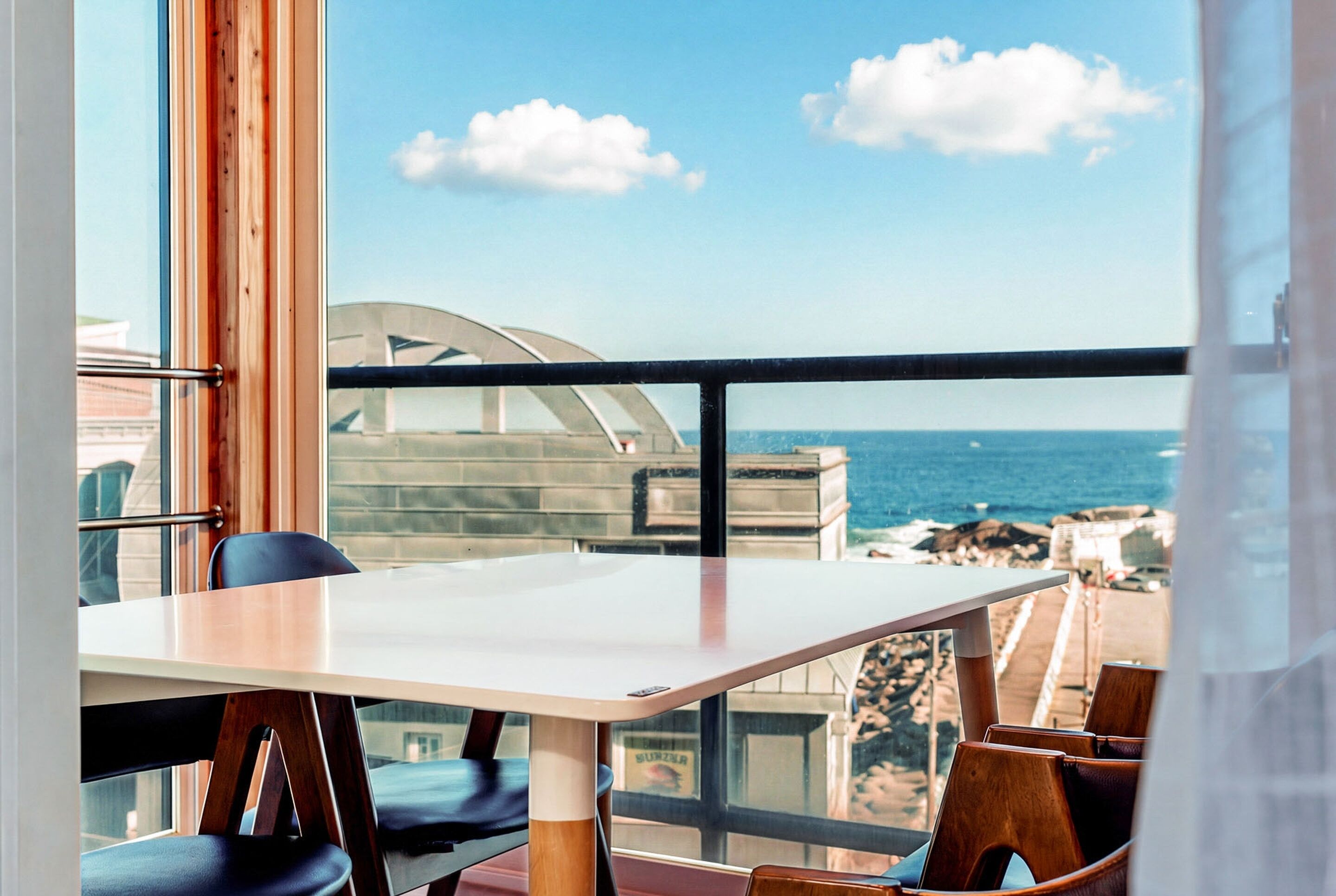 A balcony with a table and chairs overlooking the ocean.