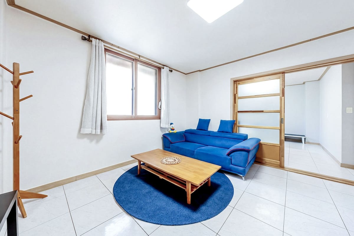 Un salon moderne avec un canapé bleu, une table basse en bois et un grand miroir.