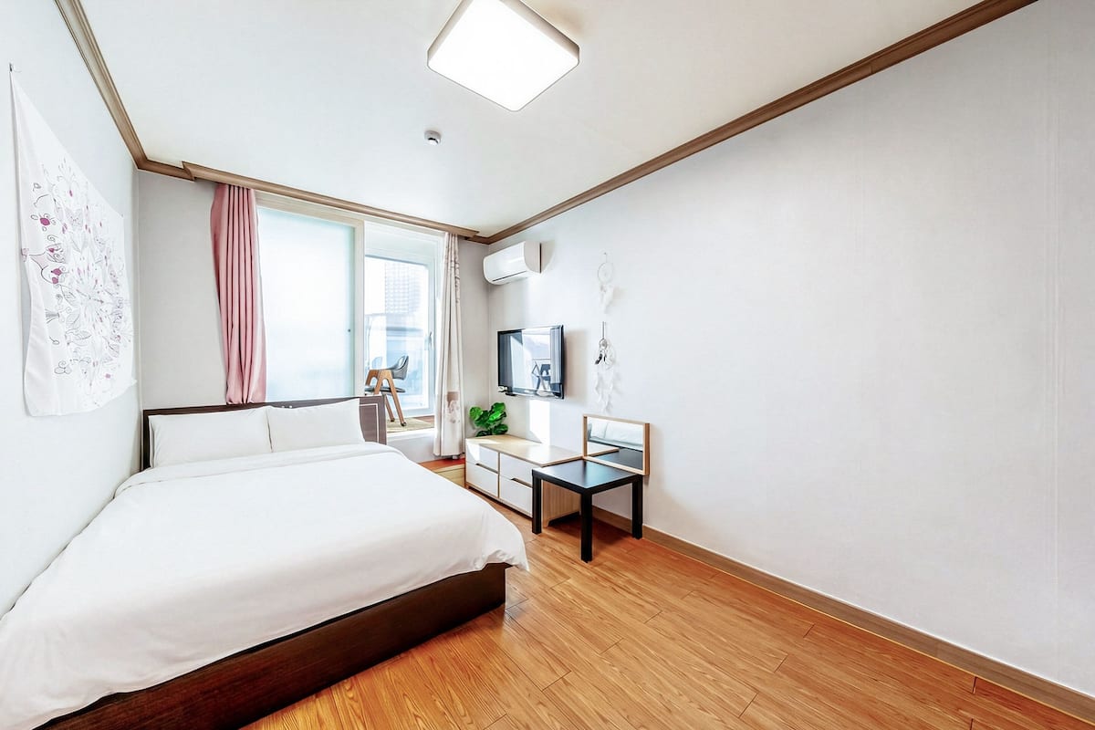Une chambre d’hôtel moderne, dotée d’un grand lit, d’un bureau avec une chaise, d’une télévision et d’une fenêtre avec des rideaux.