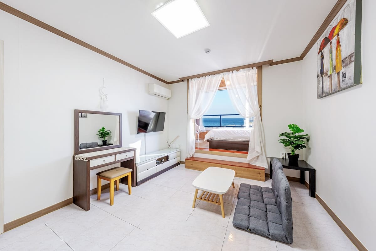Une chambre moderne avec un lit, un bureau, une télévision et une vue sur la mer.