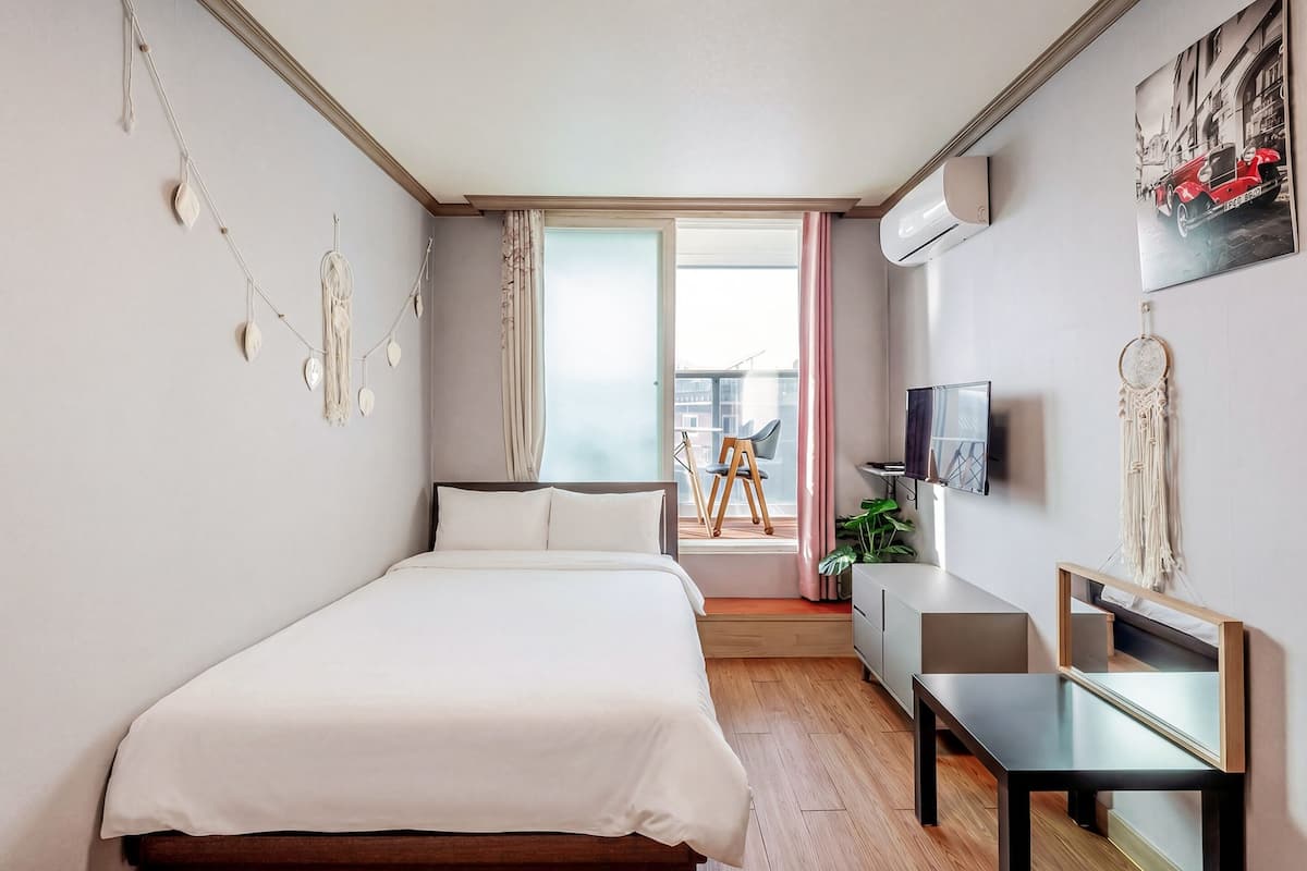 Une chambre moderne avec un lit, une table de chevet, une télévision et une vue sur le balcon.