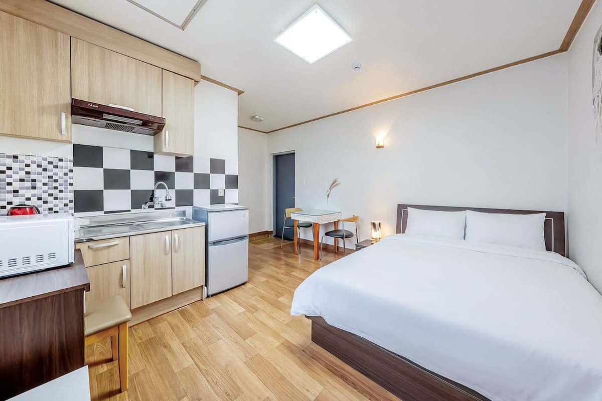 Une chambre d’hôtel compacte comprenant un coin cuisine, un lit, une petite table à manger et une chaise.