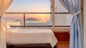Une chambre avec une grande fenêtre, un lit et des rideaux.
