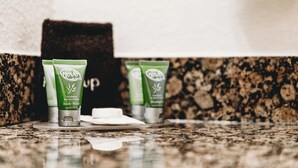 Trois tubes verts de gel douche et de shampoing sont posés sur un comptoir en granit.