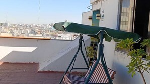 A rooftop terrace with a swing chair and a green umbrella, overlooking a cityscape. - hotel boutique Terraza Inn (Arequipa)