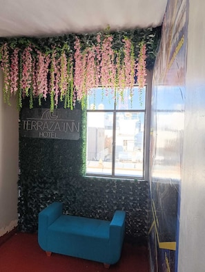 A room with a blue sofa, a window with a view, and a wall with a sign reading 'TERRAZA INN HOTEL'. - hotel boutique Terraza Inn (Arequipa)