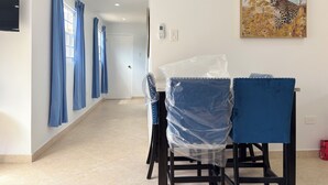 Camera d'albergo con zona pranzo, sedie blu e un tavolo, un quadro con un leopardo e pavimento piastrellato.