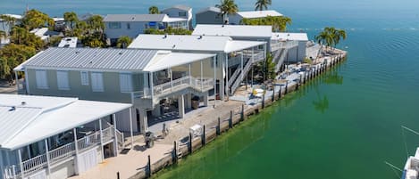 Um imóvel à beira-mar com vários edifícios, incluindo uma casa com varanda e área coberta, interligados por um cais.