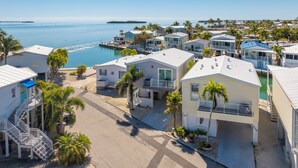 A coastal residential area with multiple two-story houses, a marina, and a clear view of the ocean. - Open Water Views |  32' Boat, King Beds, Fish Cleaning Station, Waterfront Escape (Cudjoe Key)
