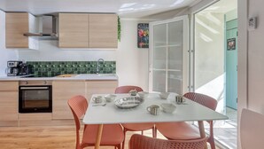 Eine moderne Küche mit Holzausstattung, einem eingebauten Backofen und einem Essbereich mit weißem Tisch und orangefarbenen Stühlen.