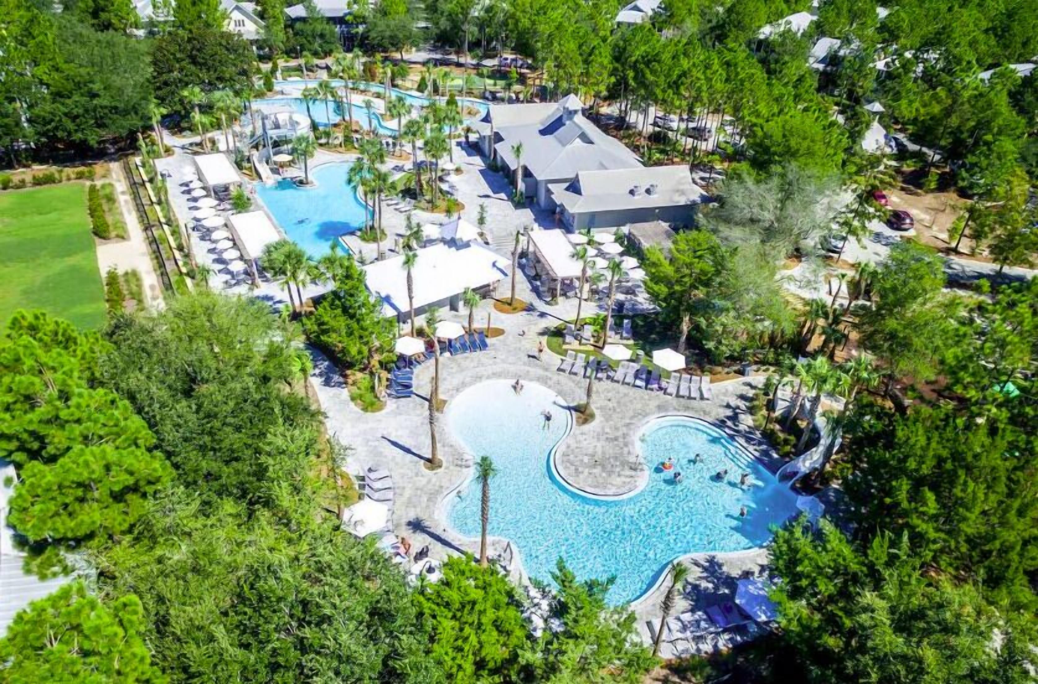 Oversigtsbillede af et resort med flere swimmingpools, loungeområder og en stor bygning.