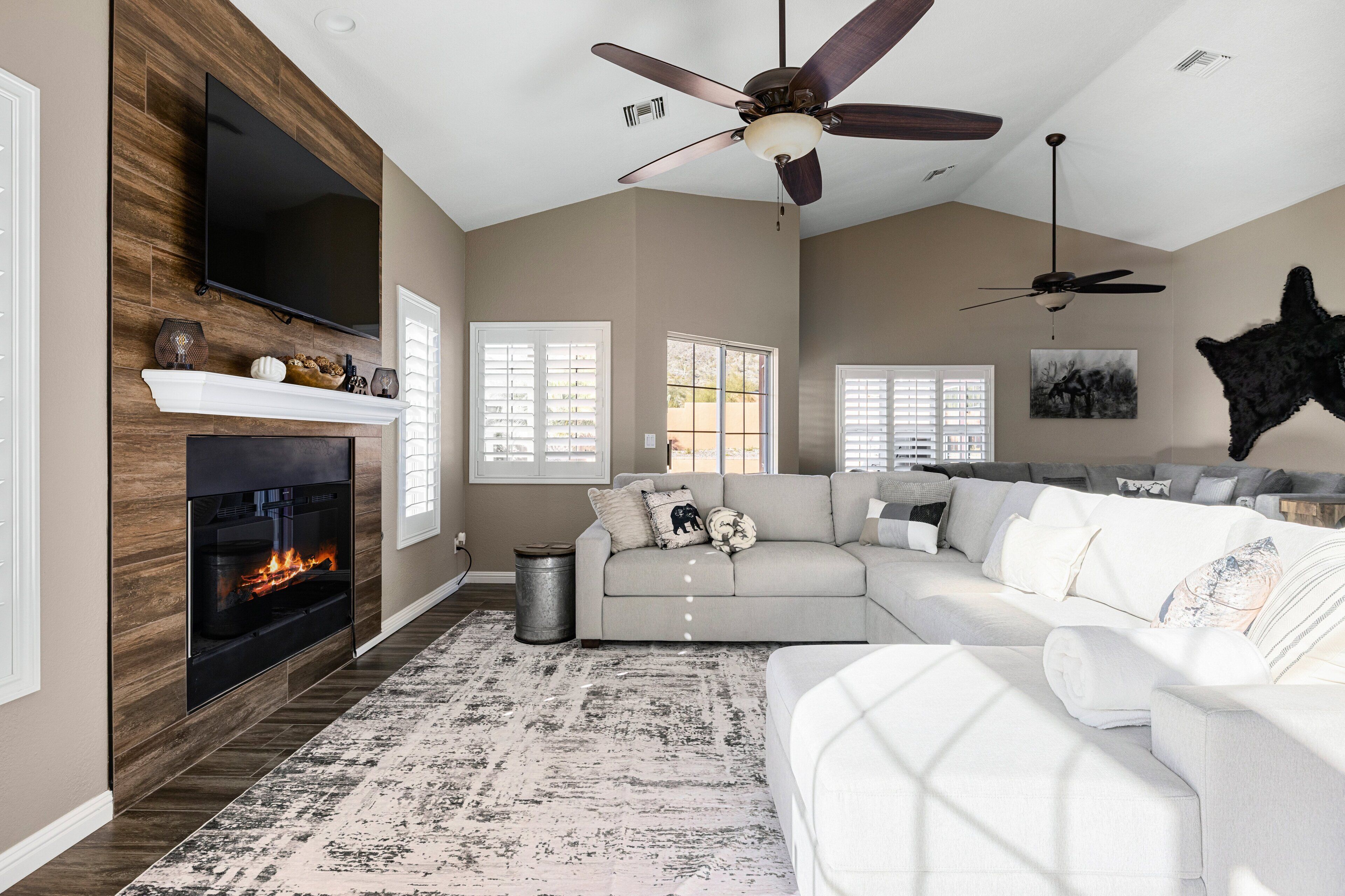A living room with a fireplace, a large sofa, and a ceiling fan.