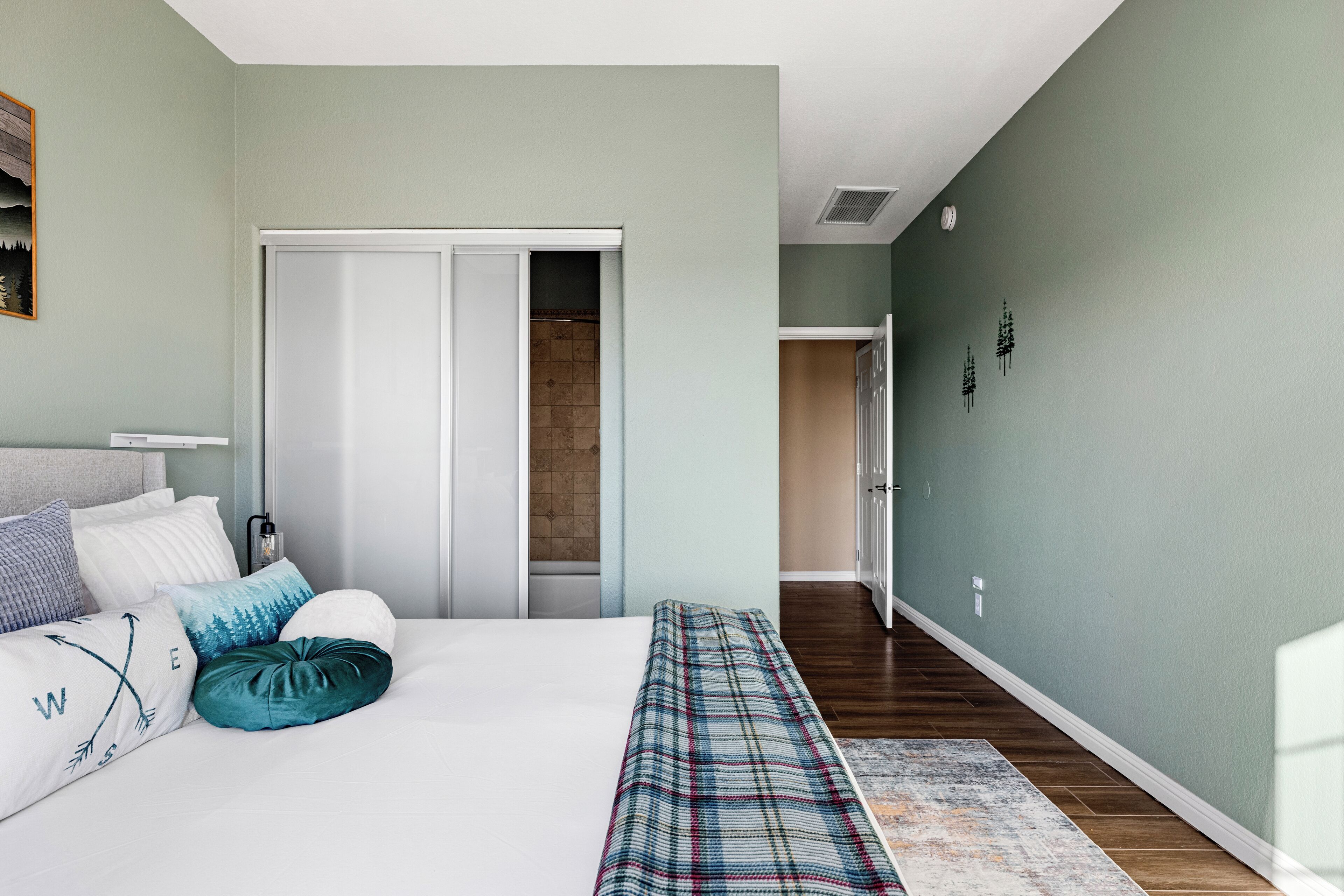 Ein Schlafzimmer mit einem Bett, Kissen, einer Bank und einer Tür zu einem Badezimmer.