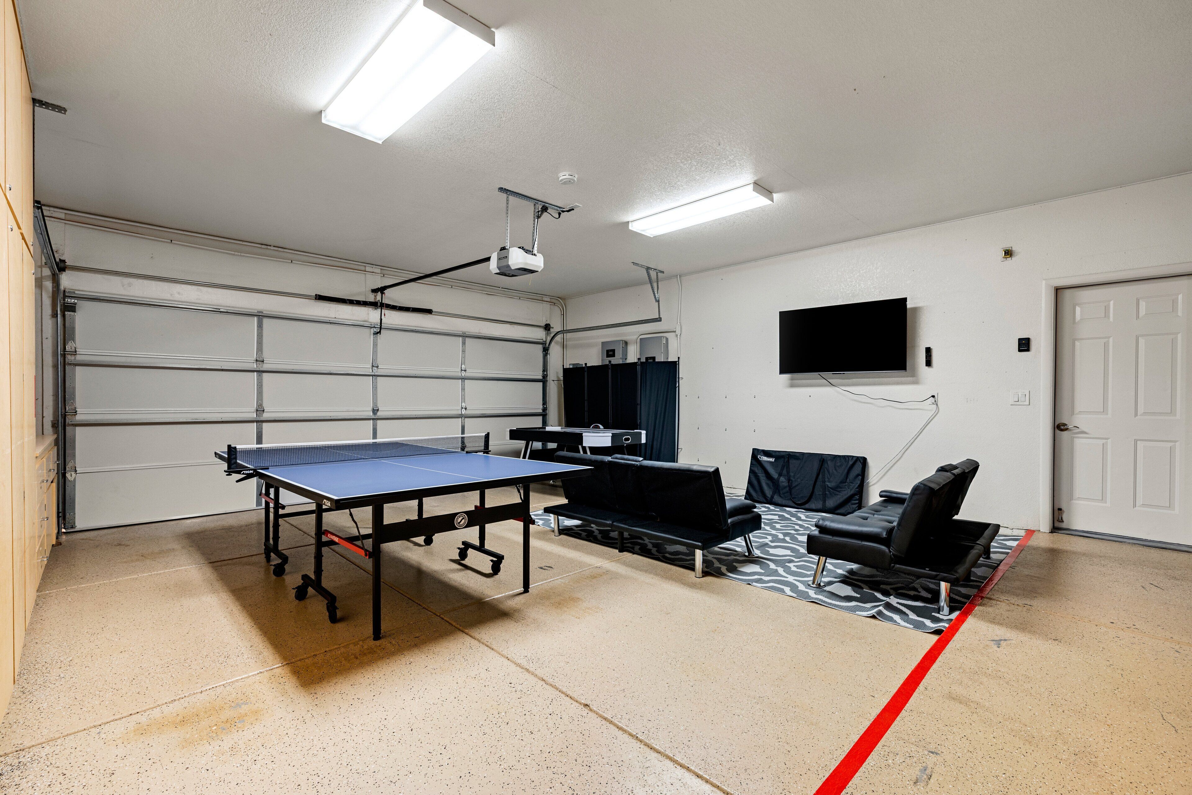 Un garage équipé d’une table de ping-pong, de chaises et d’un projecteur.