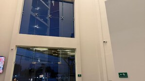 Un hall d’hôtel doté d’une grande entrée en verre, d’un escalier et d’un panneau indiquant la direction de la sortie.
