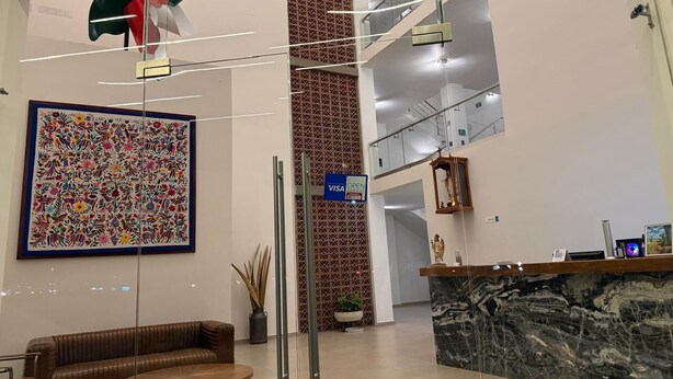 Un hall d’entrée moderne avec un comptoir d’accueil, une grande œuvre d’art aux couleurs vives, un mur orné de motifs et une porte en verre.