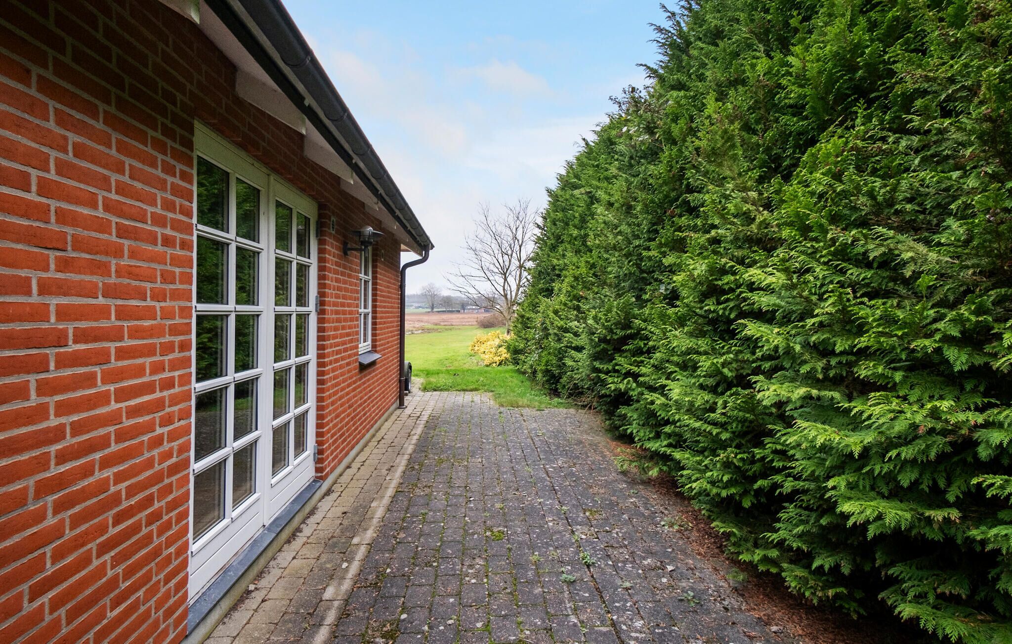 Een gebouw van baksteen met grote ramen en een geplaveid pad dat naar een groen gebied leidt.