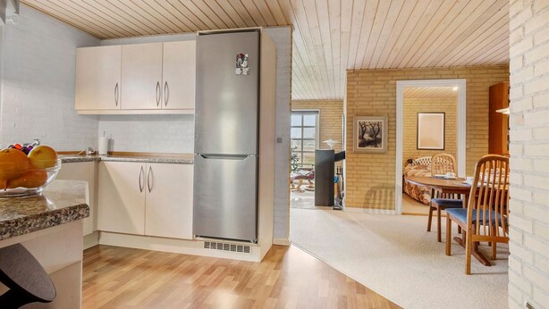 Une cuisine moderne dotée d’un réfrigérateur en acier inoxydable, de meubles en bois et d’un coin repas avec une table et des chaises.