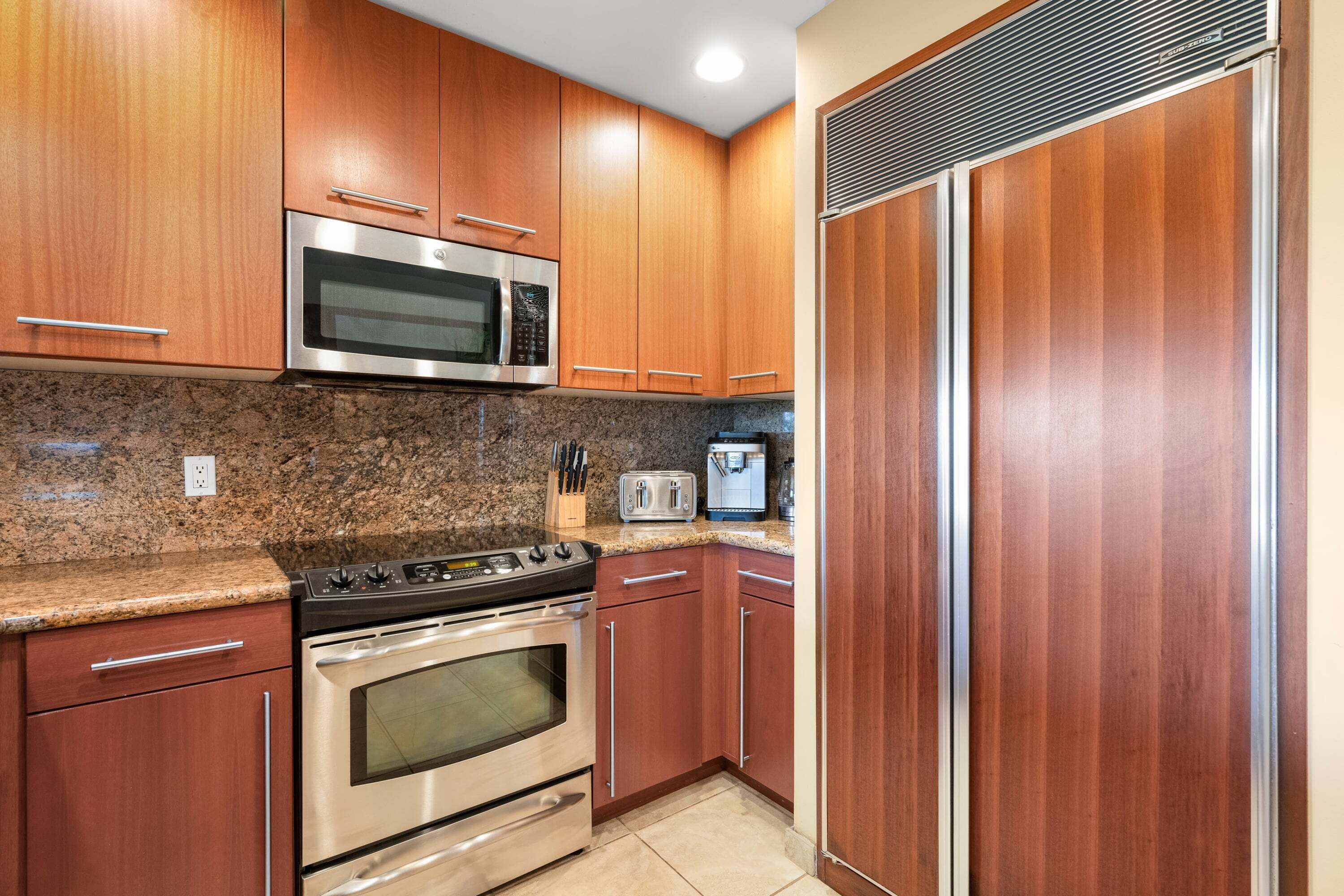 A kitchen with wooden cabinets, stainless steel appliances, granite countertop, and a built-in microwave.