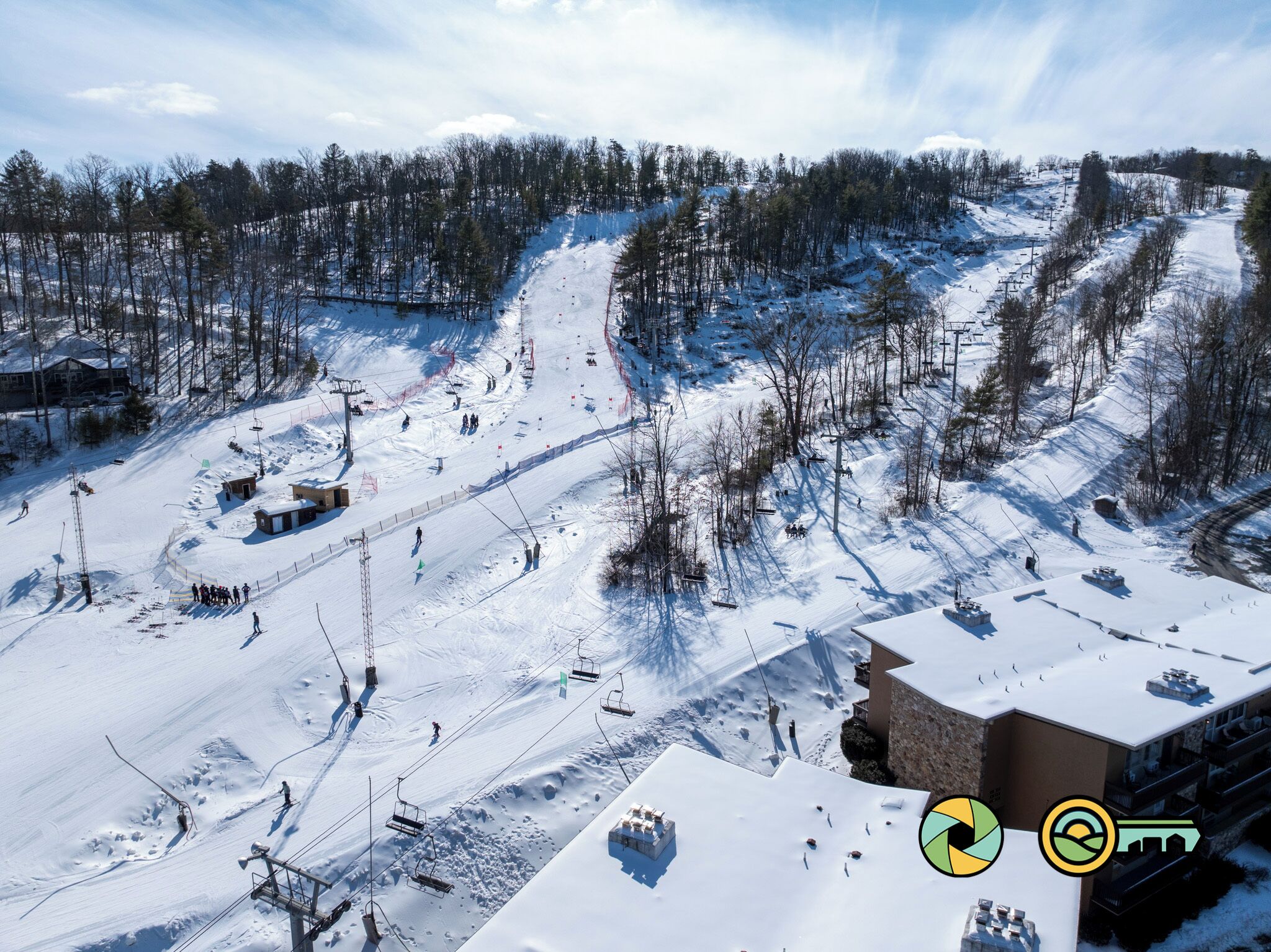 Een wintersportgebied met een stoeltjeslift, besneeuwde pistes en een bebost achtergrond.