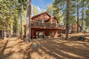A cabin with a balcony, surrounded by tall trees. - Kindred Pines at Tahoe Donner by Tahoe Getaways - 3BR with Pool Table & HOA (Truckee)