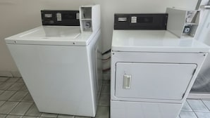 Two white washing machines in a room with tiled flooring. - Budget Inn (Durham)