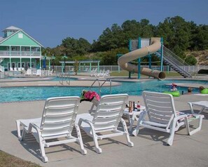 Une piscine dotée de chaises longues, d’un toboggan et d’un bâtiment surmonté d’un toit végétalisé.
